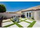 Beautiful backyard featuring a cozy outdoor dining area, lush artificial turf, and stylish concrete pavers at 6100 Cocktail Dr, Las Vegas, NV 89130