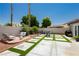 Relaxing backyard featuring an artificial turf patio with pavers, seating area, grill and lush landscaping at 6100 Cocktail Dr, Las Vegas, NV 89130