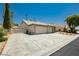 Exterior of a home with a large driveway, well-kept landscaping, and a gated yard at 6100 Cocktail Dr, Las Vegas, NV 89130
