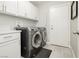 Laundry room with gray front-loading washer and dryer, white cabinets and countertops, and tile flooring at 6100 Cocktail Dr, Las Vegas, NV 89130