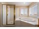 Bright bathroom featuring a garden tub next to glass-enclosed shower and shuttered windows at 6209 Exquisite Ave, Las Vegas, NV 89110