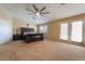 A large main bedroom with neutral colored walls, plush carpet, ceiling fan, and french doors at 6209 Exquisite Ave, Las Vegas, NV 89110