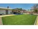 Lush backyard with artificial grass, a stone fire pit, and a covered patio for outdoor enjoyment at 671 Riata Way, Las Vegas, NV 89110