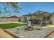 Spacious backyard featuring a stone fire pit, outdoor seating, artificial grass, and a covered patio at 671 Riata Way, Las Vegas, NV 89110