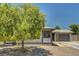 Single-story home with stucco exterior, gravel landscaping and a large, mature tree in the front yard at 671 Riata Way, Las Vegas, NV 89110