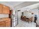 Open kitchen and dining area featuring stainless steel refrigerator, wood cabinets, and tiled flooring at 671 Riata Way, Las Vegas, NV 89110