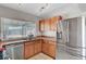 Functional kitchen with a stainless steel refrigerator, wooden cabinets, and stainless steel appliances at 671 Riata Way, Las Vegas, NV 89110