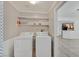 Convenient laundry room with a washer, dryer, and open shelving, with an open concept kitchen view at 6868 Sky Pointe Dr # 1107, Las Vegas, NV 89131