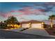 Home exterior featuring an attached three-car garage, desert landscaping and a well-maintained lawn at 8650 W Verde Way, Las Vegas, NV 89149