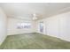Spacious bedroom with green carpet, a ceiling fan, and a large window at 9709 Casper Peak Ct, Las Vegas, NV 89117