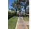 A pathway leading to a condo complex with blue awnings, surrounded by lush landscaping and mature trees at 101 Luna Way # 104, Las Vegas, NV 89145