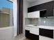Stylish wet bar features modern black and white cabinetry, stainless steel sink, subway tile backsplash and a window at 10342 Kesington Dr, Las Vegas, NV 89135