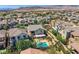 An elevated view shows houses with neutral exteriors and in-ground pools in the backyard in a desert landscape at 11844 Mino Rio Ave, Las Vegas, NV 89138