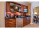 Compact kitchenette with dark wood cabinetry, mini-fridge, microwave, sink, and a wall-mounted television at 125 E Harmon Ave # 2801 & 2803, Las Vegas, NV 89109