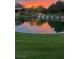 Pond reflecting a colorful sunset, surrounded by a lush green lawn and a building in the background at 18 Brookridge Dr, Henderson, NV 89052