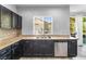 Stylish kitchen featuring dark cabinets, granite countertops, stainless steel dishwasher and a view to the backyard at 3257 Rushing Waters Pl, Las Vegas, NV 89135