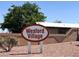 Wexford Village community sign with desert landscaping, a block fence, and a building with a white roof in the background at 5200 Paradise Skies Ave, Las Vegas, NV 89156