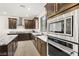 Modern kitchen with stainless steel appliances, a gourmet range hood, and beautiful granite countertops create an elegant cooking space at 11676 Midnight Melody Ave, Las Vegas, NV 89138