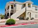 A tan condo building with staircases, desert landscaping, and a well-manicured shrub at 1881 W Alexander Rd # 2117, North Las Vegas, NV 89032