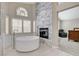 Bright bathroom boasts a soaking tub, a stone accent wall with fireplace, and a view to the bedroom at 2073 Sapphire Valley Ave, Henderson, NV 89074