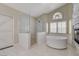 Bright bathroom boasts a soaking tub, glass shower, and a stone accent wall with a fireplace at 2073 Sapphire Valley Ave, Henderson, NV 89074