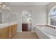 Bright bathroom featuring a soaking tub, tile floors, wood vanity, and an arched window at 2405 Esteem Ridge Dr, Henderson, NV 89052