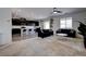 Open-concept living room with dark sofas, a ceiling fan, and a view of the kitchen area at 242 Polaris Ridge Ave, Henderson, NV 89011