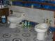 Bathroom with a toilet and bidet sitting on a patterned tile floor with a white, blue, and gold colored wall at 6325 Burgundy Way, Las Vegas, NV 89107