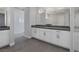 Bathroom featuring double sinks with white cabinets and dark countertops, complemented by gray tile flooring at 8838 Sorrel Hills Ct, Las Vegas, NV 89113