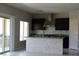Modern kitchen with stainless steel appliances, dark cabinets, island and sliding glass door at 9065 Mastodon Ave, Las Vegas, NV 89149