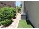 Side yard featuring gravel, bushes, air conditioning unit, artificial turf and gate at 9065 Mastodon Ave, Las Vegas, NV 89149