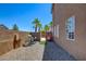 Side yard of house featuring a rock bed, partial fence, palm trees, and utilities equipment at 98 Milicity Rd, Henderson, NV 89012