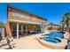 Backyard oasis featuring a pool, spa, covered patio, string lights, and palm trees at 98 Milicity Rd, Henderson, NV 89012