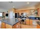 This open kitchen features stainless appliances, granite countertops, a kitchen island and wood cabinets at 98 Milicity Rd, Henderson, NV 89012