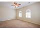 Large carpeted bedroom with arched shuttered windows and a ceiling fan at 2131 Sandstone Cliffs Dr, Henderson, NV 89044