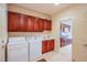 Functional laundry room with wooden cabinets, sink, and washer/dryer near the kitchen at 2131 Sandstone Cliffs Dr, Henderson, NV 89044