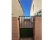 A backyard gate leads to a brick paved area, framed by symmetrical beige homes under a clear blue sky at 2713 Abrantes Pl, Henderson, NV 89044