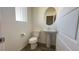 White powder room with pedestal sink, elongated toilet, and wood flooring at 2713 Abrantes Pl, Henderson, NV 89044