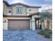 Two-story home with tan siding, brown trim, a two car garage, and a beautiful brick paver driveway at 302 Bay Village Pl, Henderson, NV 89011