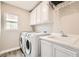 Well-equipped laundry room with white cabinets, modern washer and dryer, and a sink at 3437 Visionary Bay Ave, North Las Vegas, NV 89081