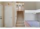 View of the carpeted staircase leading to the second floor of this home with a large open living space and a white door on the left at 4280 Cicada Way, Las Vegas, NV 89121