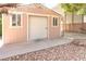 Exterior view of a backyard storage shed with a roll-up door and adjacent covered storage at 5193 N Miller Ln, Las Vegas, NV 89149