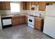Well-equipped kitchen features warm wood cabinets, white appliances, and tile flooring at 5969 High Steed St # 101, Henderson, NV 89011