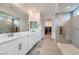 Bathroom features double sinks, white cabinets, a large mirror, and a glass enclosed shower with tiled walls at 6519 Summershade St, North Las Vegas, NV 89086