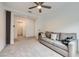 Inviting living room featuring a comfortable gray sofa, plush carpeting, and a modern ceiling fan for added comfort at 6519 Summershade St, North Las Vegas, NV 89086