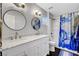 Updated bathroom features double sinks, marble countertop, modern fixtures and shower with blue and white curtain at 6647 Montezuma Castle Ln, North Las Vegas, NV 89084