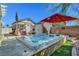 Inviting backyard featuring a hot tub, charming shed, and a vibrant red umbrella for a relaxing retreat at 6647 Montezuma Castle Ln, North Las Vegas, NV 89084
