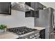 Updated kitchen with stainless steel appliances and a modern vent hood over a gas range at 7713 White Grass Ave, Las Vegas, NV 89131