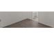 An empty room with wood-look flooring, white walls, and a doorway leading to a bathroom at 8843 Tomnitz Ave # 102, Las Vegas, NV 89178