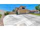 View of the house with an expansive concrete driveway, lawn, and a three-car garage for ample parking at 8914 Termoli St, Las Vegas, NV 89123